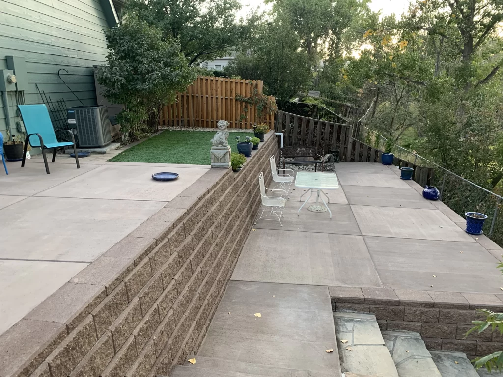 Concrete block retaining wall supporting a multi-level patio on a sloped Denver yard