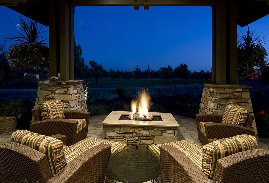 Covered patio seating area lit at dusk around a fire table